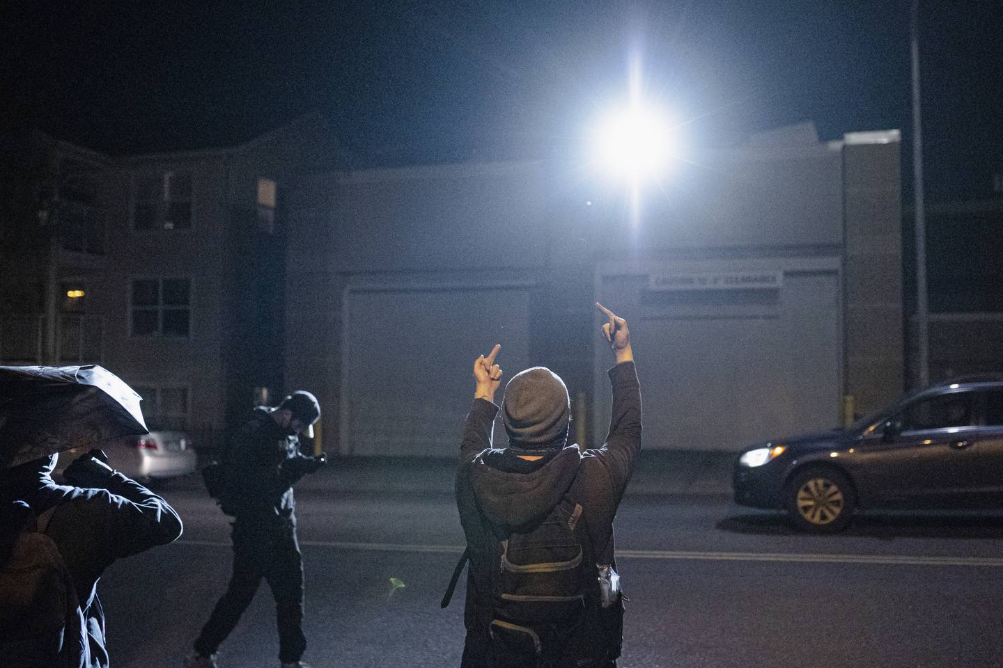A protester gives two middle fingers to a police building.