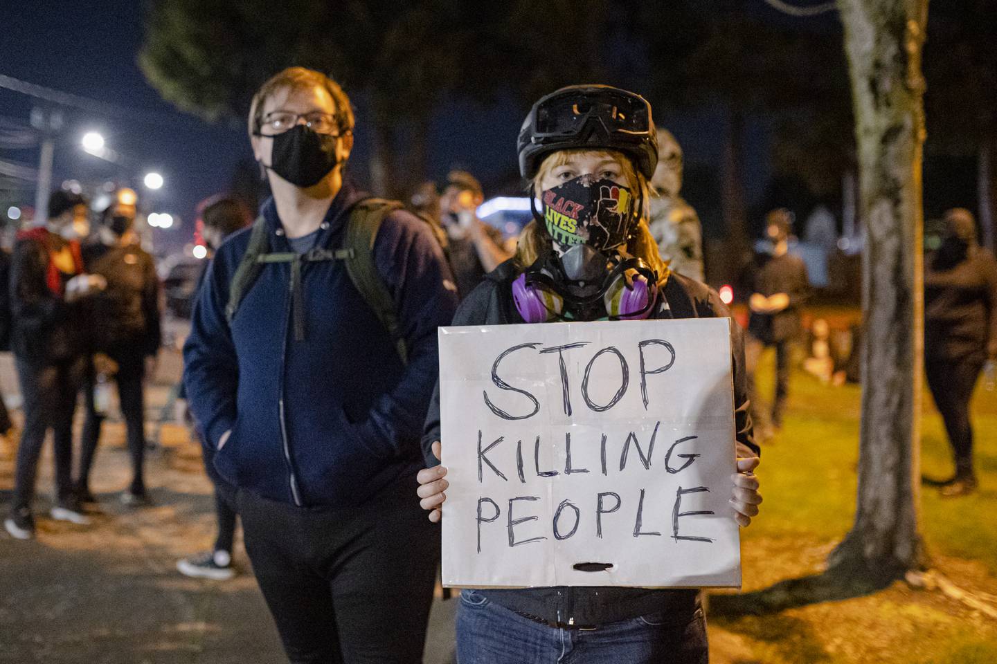 Protesters hold a sign that reads, "Stop Killing People."